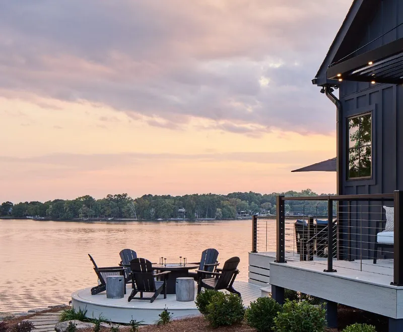 Lakeside composite deck at sunset with Trex Signature X-Series cable railing and Adirondack chairs around a fire pit