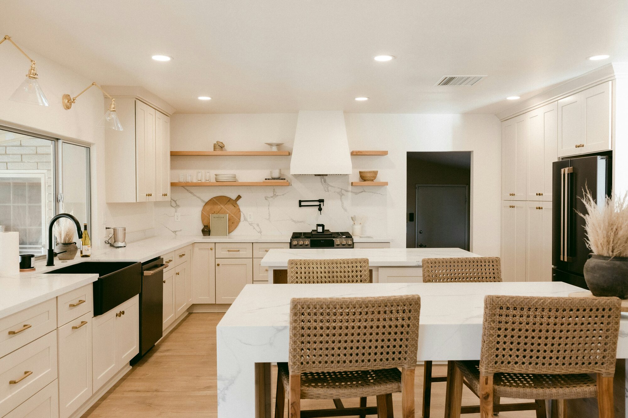 Custom white shaker kitchen with marble island, gold hardware, and rattan bar stools