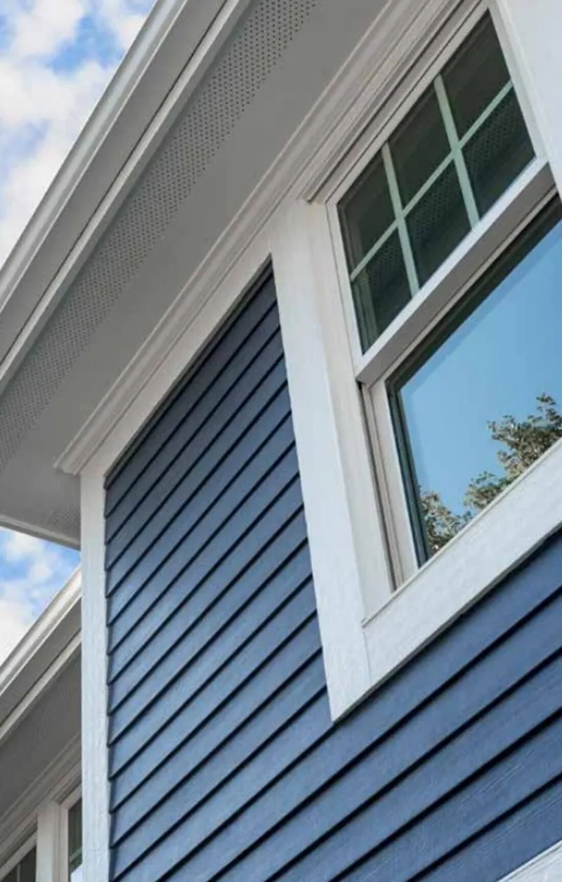 Close-up of navy blue James Hardie plank lap siding with white trim and soffit
