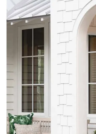 White Cape Cod home detail showing James Hardie staggered edge shingle siding next to an arched window